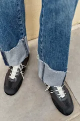 Jeans baggy de tiro medio con pernera holgada, diseño de cinco bolsillos y bajo acabado en vuelta. Cuenta con cintura elástica en la espalda y cierre frontal con cremallera y botón.