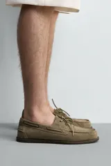 Zapato náutico de hombre confeccionado en piel con acabado en serraje, color marrón claro, con detalles de cordones y ojales metálicos.