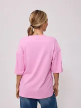 Remera blanca de algodón con estampado frontal de estilo playero con texto en color coral y azul.