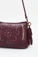 Cartera de cuero vacuno color negro con diseño de mandala floral bordado y tachas metálicas decorativas. Cuenta con correa ajustable, cierre superior y detalle de flecos laterales.