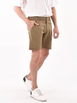 Bermuda de vestir color verde militar, de corte recto y largo hasta la rodilla, con bolsillos delanteros y cierre de botón y cremallera.