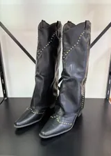 Botas texanas negras de caña alta con detalles de tachas doradas.