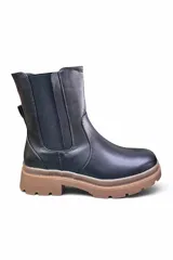 Bota de caña media estilo chelsea, color negro, con elásticos laterales y suela track marrón con plataforma dentada.