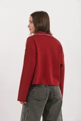 Sweater de punto color rojo con cuello polo, cierre frontal parcial con botones y detalle de costura en contraste a lo largo de la tapeta.