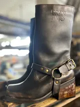 Botas de cuero color marrón oscuro, de caña media, con detalle de estribo desmontable con hebilla dorada.