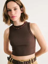 Top corto marrón de tela acanalada, con cuello redondo y sisas anchas.