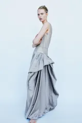 Vestido largo de tirantes con escote redondo, confeccionado en mezcla de viscosa. Presenta un diseño combinado con la parte superior en tejido ligero semitransparente y la parte inferior con volumen y drapeado asimétrico.