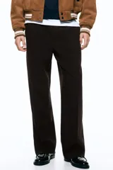 Pantalón relaxed fit color marrón, confeccionado en tejido suave, con cintura elástica ajustable mediante cordón, bolsillos laterales discretos, bolsillo posterior insertado y piernas rectas con pliegues frontales y traseros.