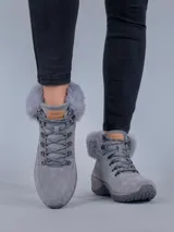 Botas de estilo montañés color gris, confeccionadas en cuero y poliéster. Presentan cuello con forro de piel sintética, ajuste mediante cordones con ganchos metálicos y suela de goma con tecnología Spinal Flex para mayor confort.