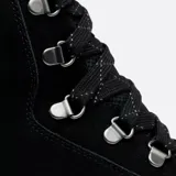 Bota de caña alta Sorel Kinetic Impact, color negro, con cordones y ojales metálicos. Suela de goma blanca con diseño geométrico.