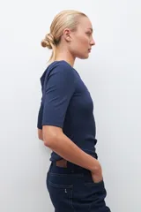 Remera verde de tejido canalé con cuello redondo y media manga. Tiene una abertura frontal con botones.