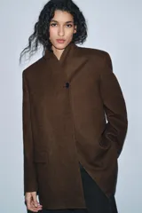 Blazer marrón de la colección Zara Woman, confeccionada en hilatura con 38% lana. Presenta cuello subido, manga larga con abertura y botones, bolsillos con solapa en el delantero y forro interior. Cierre frontal con un botón.