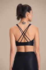 Top deportivo de compresión media con diseño de espalda cruzada y breteles finos. Confeccionado en tejido acanalado con un acabado de brillo sutil, cuenta con copas removibles y tecnología de ajuste adaptable.