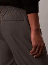 Pantalón tipo jogger de corte regular y estilo formal, confeccionado en tejido elástico de nailon y elastano. Presenta cintura elástica, bolsillos laterales y un diseño de pierna recta con acabado pulido.