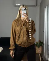 Campera tipo bomber confeccionada en gamuza, con cierre frontal metálico y detalle de flores bordadas en relieve en el frente.