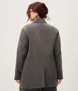 Blazer sastrero oversize color gris, de doble botonadura cruzada, solapas anchas, bolsillos delanteros embutidos y mangas largas.
