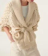 Cárdigan color crema de tejido calado con mangas abullonadas y cinturón para atar.
