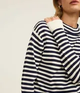 Sweater de punto de manga larga, con rayas horizontales en azul marino y blanco. Presenta cuello redondo ligeramente elevado y puños y ruedo en color blanco liso.