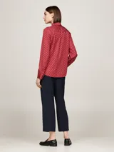 Blusa roja con estampado de rombos blancos, cuello con lazo y mangas largas con puños abotonados.