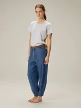 Pantalón de jean con silueta relajada, tiro medio y botamangas con elástico. Presenta costuras verticales frontales, bolsillos laterales y cierre frontal con botón.