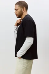 Remera negra de algodón pesado, corte holgado, con cuello redondo ribeteado, hombros caídos y bajo recto.