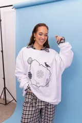 Buzo de cuello redondo en color blanco, con diseño estampado en el centro que incluye el contorno del mapa de Uruguay y símbolos nacionales como el sol, el mate y el hornero.