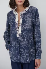Blusa de manga larga con estampado floral en tonos azul marino y crema. Presenta un escote en V con tapeta abotonada en contraste y un corte holgado.