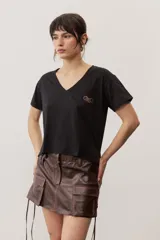 Remera de manga corta color negro, de corte clásico y escote en V, con sutil detalle bordado en el pecho.