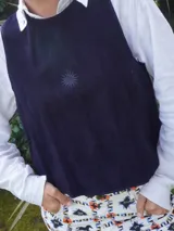 Chaleco de gamuza negro, sin mangas, con cuello redondo y diseño bordado de un sol en el pecho.