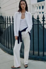 Camisa blanca de algodón con cuello solapa, manga larga y cierre frontal de botones.