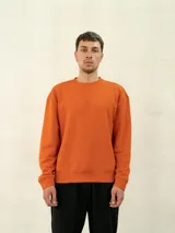 Buzo básico de felpa color naranja, con cuello redondo y logo de Umbro bordado en el pecho.