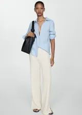 Pantalon de crochet color crema, de corte recto y tiro alto con cintura elástica. Presenta un diseño de tejido calado con aberturas laterales en el bajo.