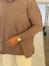 Polerón de punto color visón con cuello alto holgado, mangas largas con puños acanalados y diseño de corte amplio.