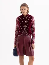 Chaleco de velvet color bordó con estampado floral, cuello mao y terminaciones con vivo en contratono. El acceso es mediante cruce diagonal con broches dorados. Tiene pinzas delanteras y traseras que le dan un fit al cuerpo y un sutil efecto evasé en la parte inferior.