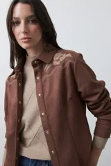 Sobrecamisa de gamuza color marrón con bordados decorativos estilo western en la zona de los hombros y cierre frontal con botones metálicos.