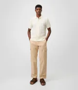 Pantalón cargo de corte recto en color beige, confeccionado en tejido de sarga de algodón. Cuenta con bolsillos laterales y bolsillos cargo con solapa en las piernas, cintura con pasacintos y cierre frontal con botón y cremallera.
