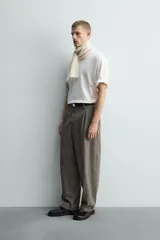 Pantalón de corte relajado con diseño de cuadros, confeccionado en tejido con lana. Presenta cintura con pliegues frontales, bolsillos laterales y bolsillos traseros de vivo, con cierre frontal de cremallera y gancho metálico oculto.