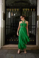 Vestido verde brillante, con escote halter anudado al cuello, aberturas laterales (cut-outs) y falda asimétrica con volados en el ruedo.