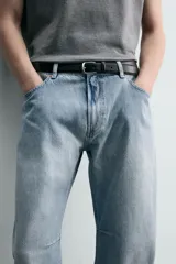 Jeans de denim de algodón en color negro con efecto lavado, corte amplio y silueta curva tipo barrel fit con pinzas en las rodillas. Presenta diseño clásico de cinco bolsillos y cierre frontal con cremallera y botón metálico.