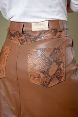 Pollera midi de cuero ovino con diseño tipo jean, cierre frontal con botón y tajo central.