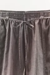 Pantalón bombacho de tiro medio con estampado de rayas verticales finas. Presenta cintura elástica con cordón ajustable, bolsillos laterales, costuras decorativas marcadas y bajo abullonado con elástico.