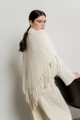 Chal de punto color crudo con textura suave y terminaciones con flecos largos en todo el borde.