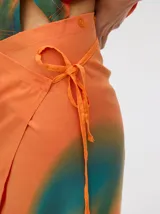 Falda midi tipo pareo color verde con estampado estilo tie-dye en tonos azul, naranja y blanco, con tiras ajustables en la cintura.