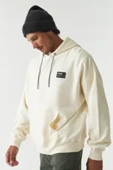 Canguro color crema con capucha ajustable, lettering estampado en el frente, logo en grifa de goma y puños.