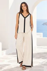 Musculosa color beige con ribetes negros en el escote en V, sisas y bandas verticales al frente.