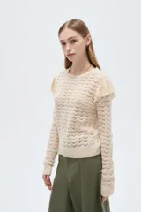 Sweater de algodón color natural, de punto con diseño calado, cuello redondo a la base y mangas largas con volados en los hombros.