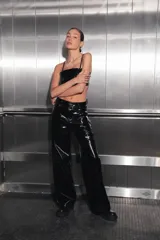 Pantalón de tiro medio-alto confeccionado en charol negro, con diseño de cinco bolsillos, cierre frontal con botón metálico y corte recto.