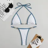 Bikini de dos piezas con corpiño triangular y bombacha colaless. El diseño destaca por sus detalles de cadenas doradas con perlas incrustadas en los breteles del corpiño y en los laterales de la bombacha. Presenta una combinación de colores vibrantes en amarillo y naranja.