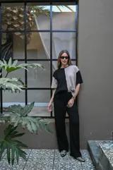 Remera de tejido de punto, manga corta, con diseño bicolor en negro y beige. La prenda es de corte holgado y presenta un ligero acanalado vertical.