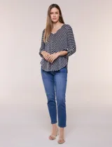 Remera de calce relajado y silueta fluida, con escote en V y mangas tres cuartos con presilla y botón. Diseño de rayas dispuestas en ángulo tipo espiga en el delantero y ruedo redondeado.